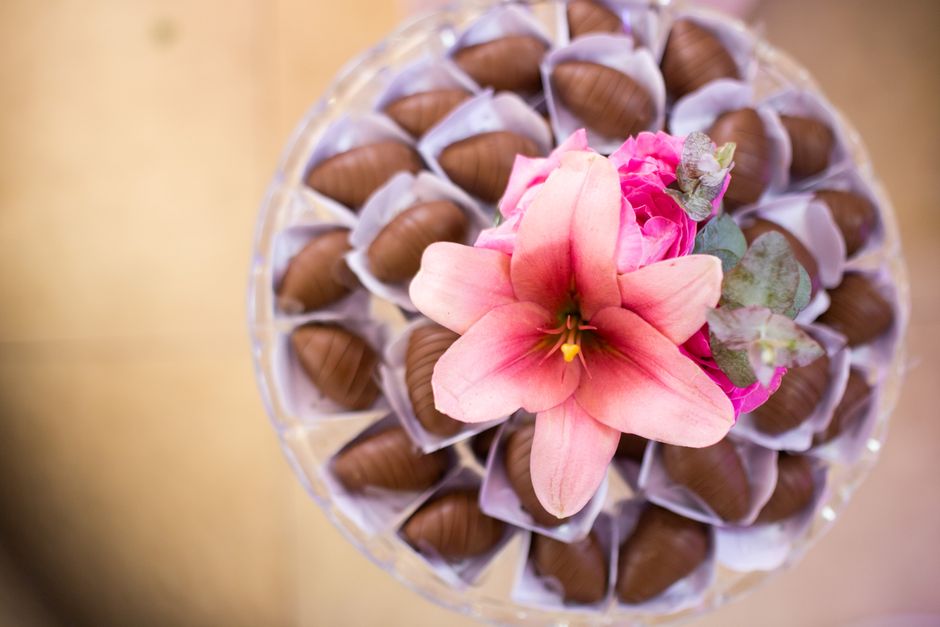 Assortiment de chocolats en forme de roses avec une fleur rose au centre, sur un plateau élégant.