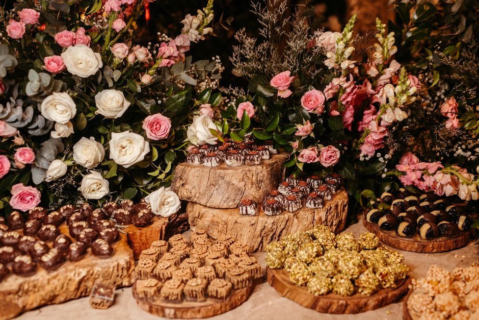 Assortiment de chocolats élégamment présentés sur des plateaux en bois, entourés de fleurs colorées.
