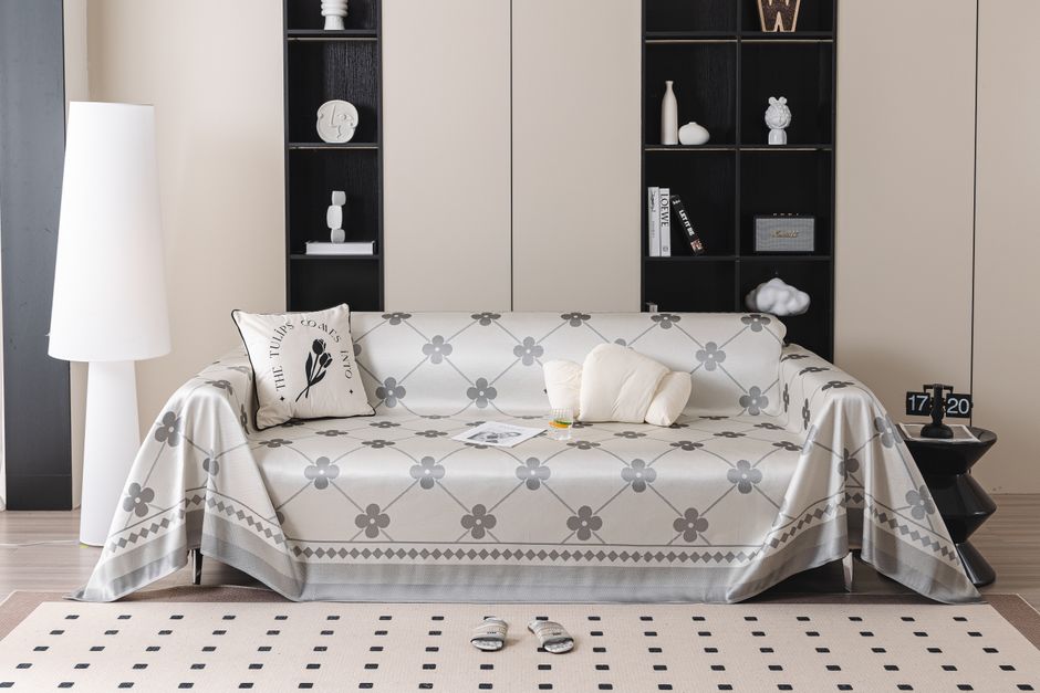 Canapé confortable avec un plaid à motifs floraux, coussins et un tapis doux, créant une ambiance cocooning.