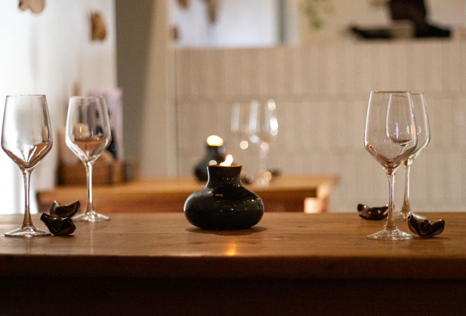 Table élégamment dressée avec des verres à vin, une bougie et des éléments décoratifs pour une ambiance chaleureuse.