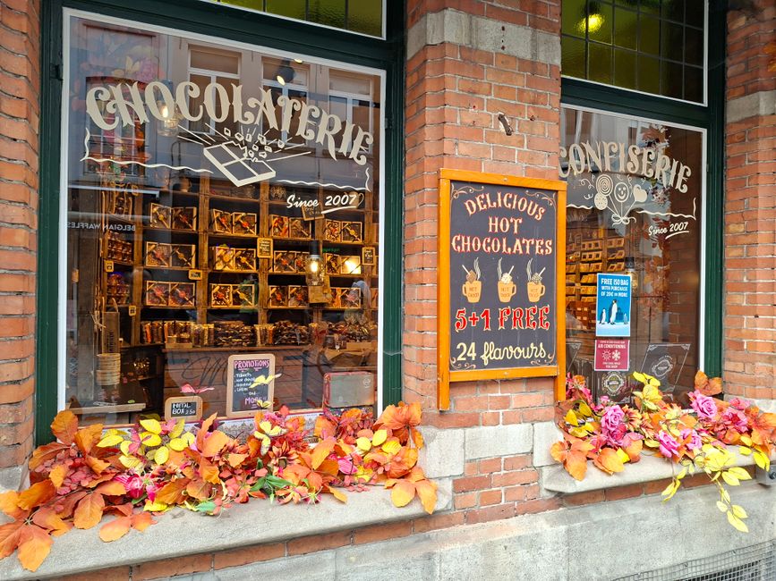 Vitrine d'une chocolaterie avec des décorations automnales et des affiches de produits chocolatés.