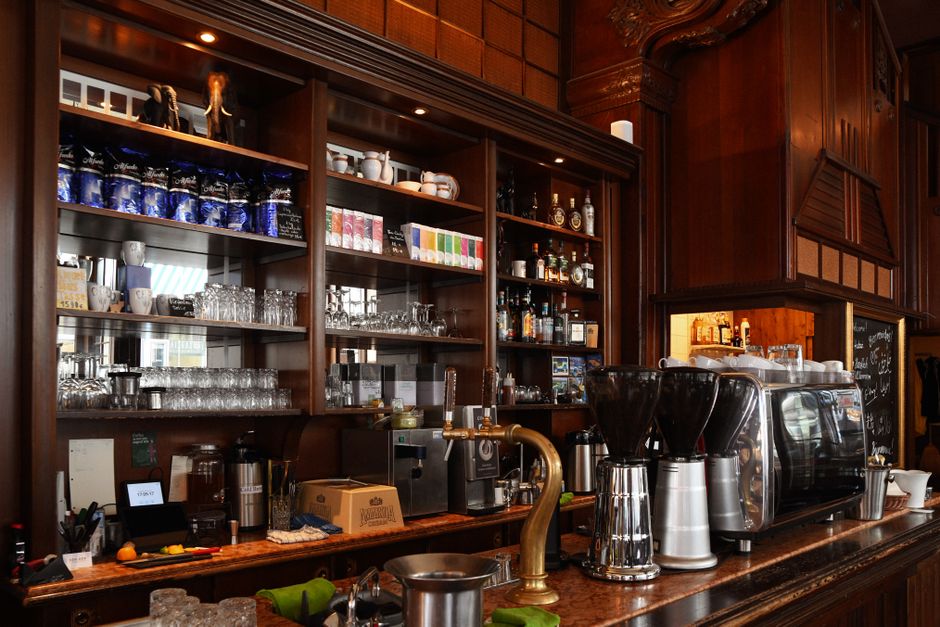 Bar à café élégant avec étagères en bois, machines à café et verres, idéal pour une pause gourmande en ville.