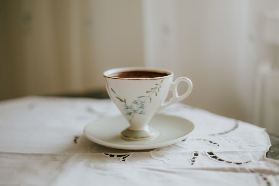 Tasse de café élégante sur une soucoupe, posée sur une nappe blanche, évoquant des moments de convivialité.
