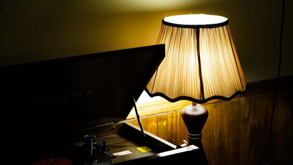 Lampe vintage éclairant un tourne-disque, créant une ambiance chaleureuse et intime.