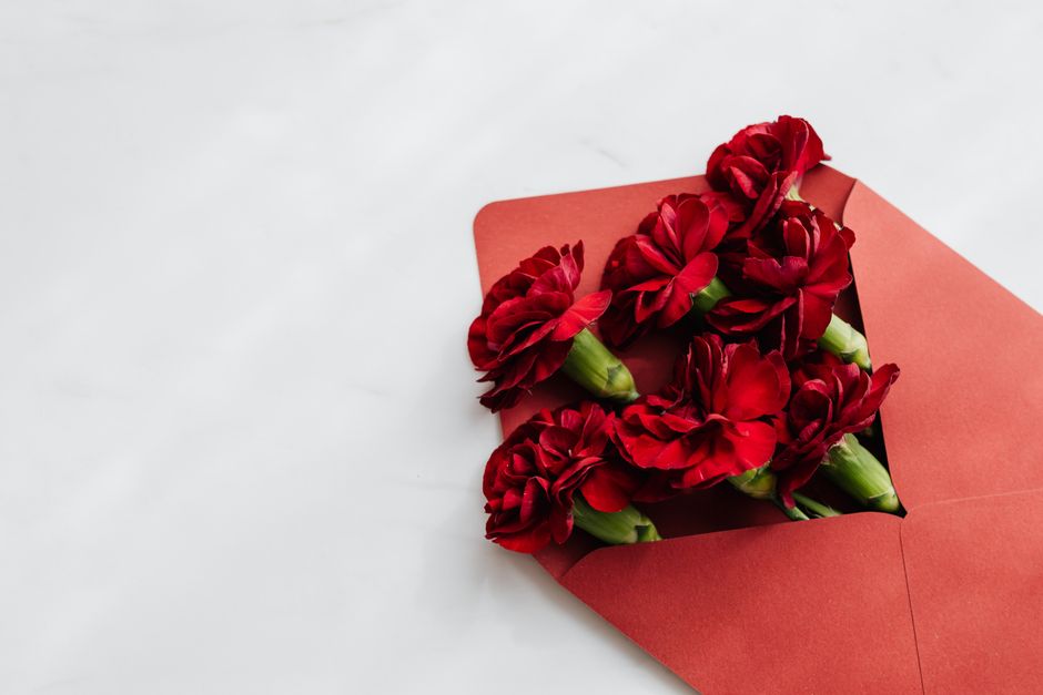 Fleurs rouges dans une enveloppe rouge, symbole de remerciement et d'attention.