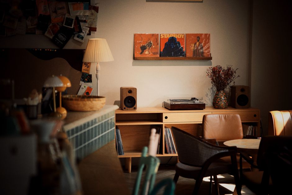 Intérieur d'un café avec une platine vinyle, des albums sur une étagère et une ambiance chaleureuse.