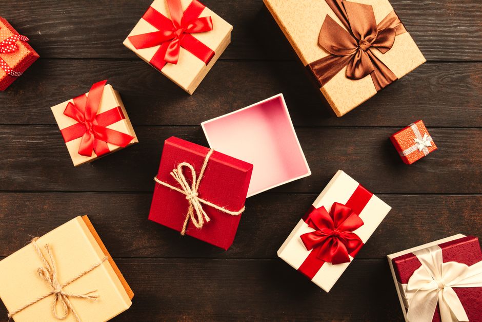 Cadeaux colorés avec des rubans sur une table en bois, certains ouverts, illustrant l'effet waouh d'un cadeau inattendu.