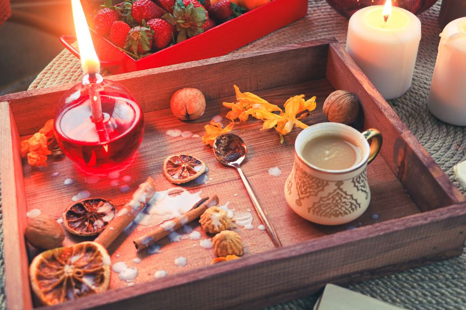 Plateau en bois avec des fruits, épices, bougies et une tasse de boisson chaude évoquant des souvenirs olfactifs.