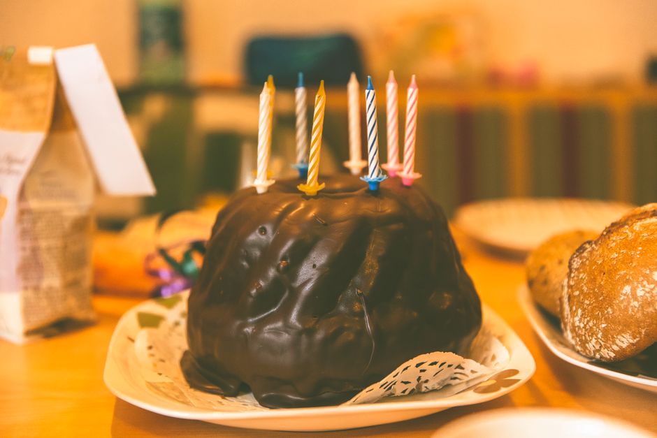 Gâteau d'anniversaire au chocolat avec des bougies colorées sur une table festive.