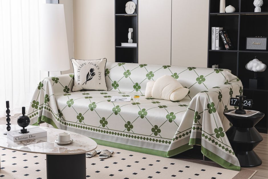 Canapé décoré d'un plaid à fleurs vertes, table basse avec objets de décoration, ambiance cocooning et chaleureuse.