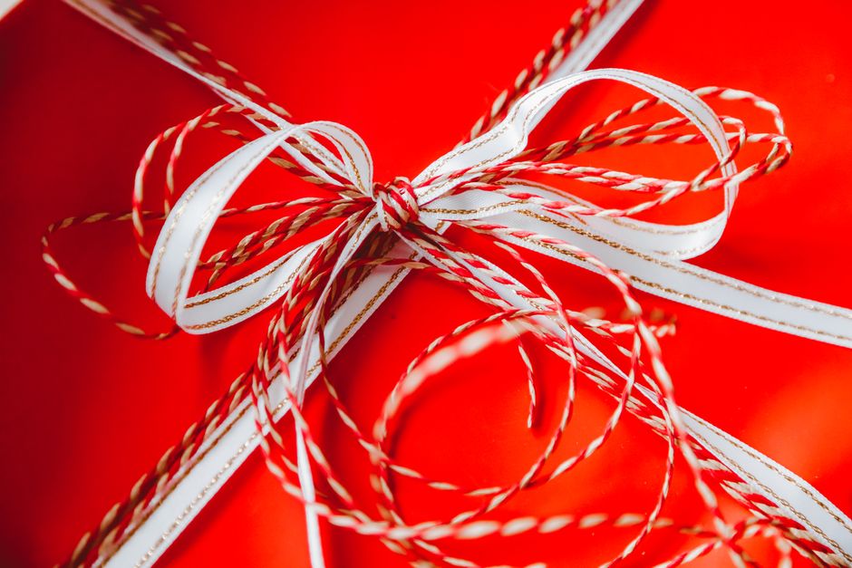 Cadeau rouge avec un nœud en ruban blanc et rouge, symbolisant l'idée de cadeaux sensoriels.
