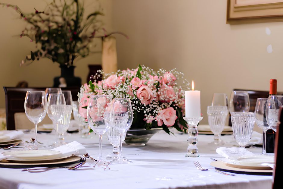 Table de fête élégamment dressée avec un bouquet de roses et de gypsophile, bougie allumée et vaisselle raffinée.